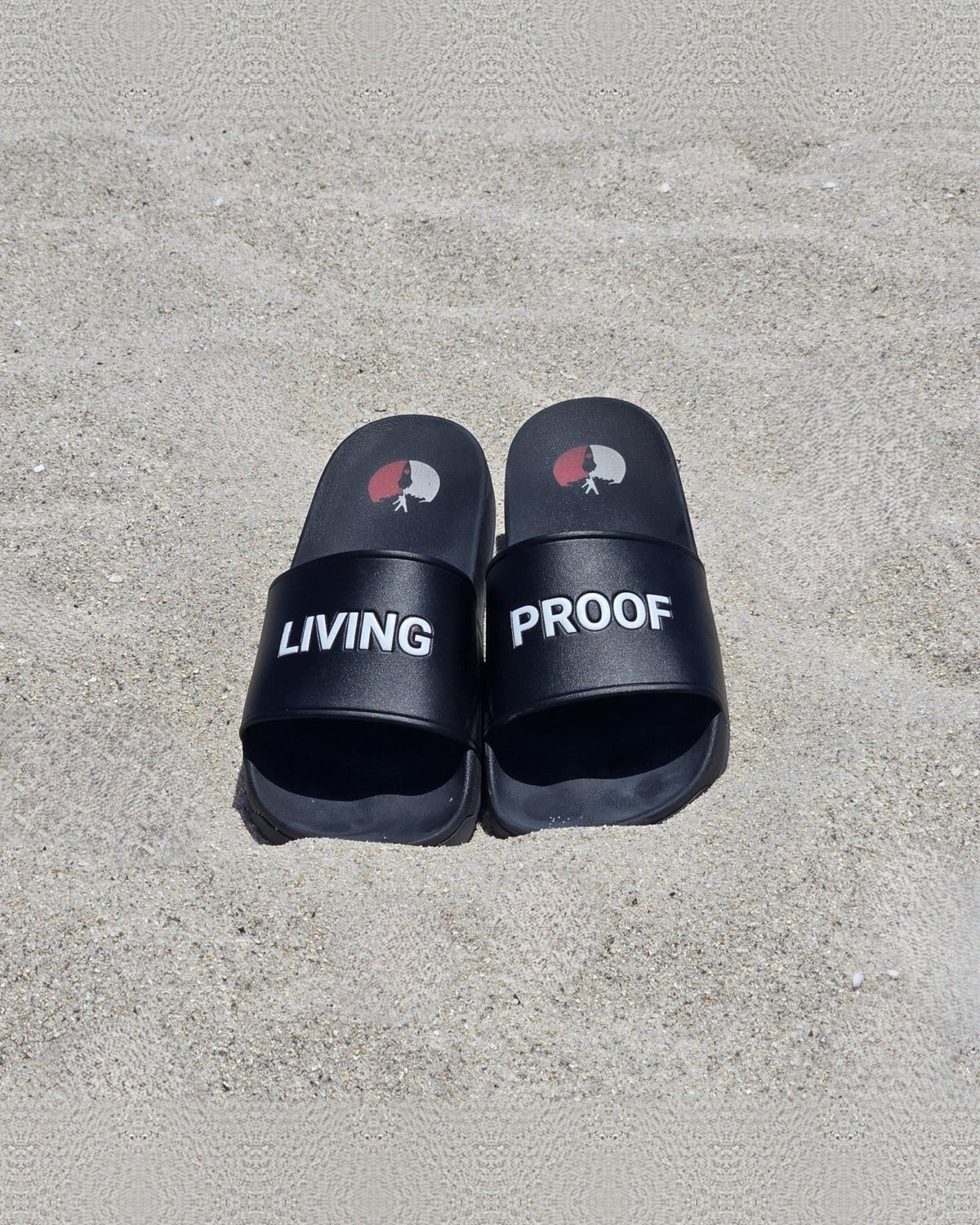 Living Proof slides on sand, LIVING and PROOF printed across the straps