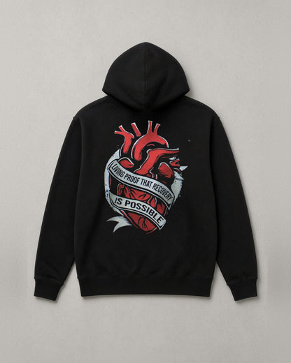 Unchained Heart hoodie back print: red heart wrapped in a banner reading Living Proof That Recovery Is Possible
