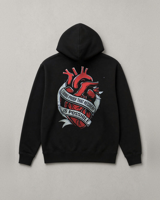 Unchained Heart hoodie back print: red heart wrapped in a banner reading Living Proof That Recovery Is Possible